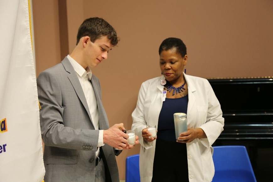 PTK Upsilon Delta Chapter President Connor Taylor lights a candle with PTK Vice President KaTanya Warner during the chapter’s 2022 induction ceremony. 