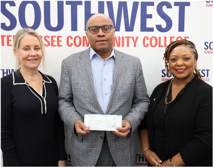 Three people pose in front of a Southwest Tennessee Community College backdrop as the center person presents a check to the Southwest Tennessee Community College Foundation.