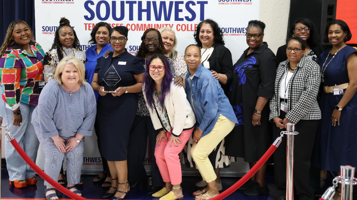 (center) Tujuana Townsend holds the Administrative Staff of the Year Award surrounded by her team.