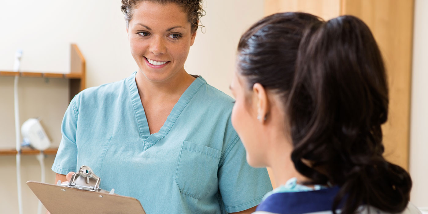 nurse on phone while patient is standing next to her